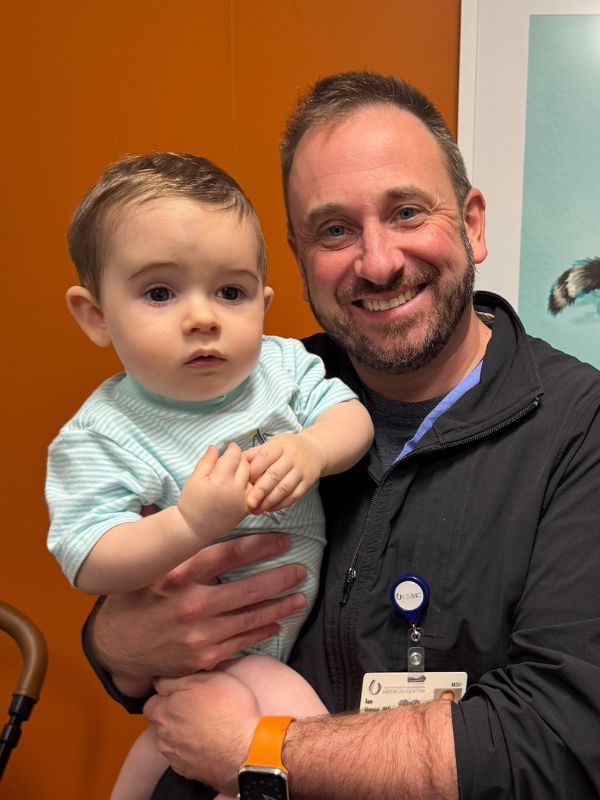 A front view of young boy after surgery for craniosynostosis, held by the doctor.